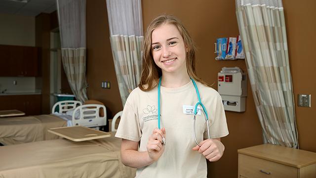 Early College student wearing C N A scrubs with a stethoscope around her neck